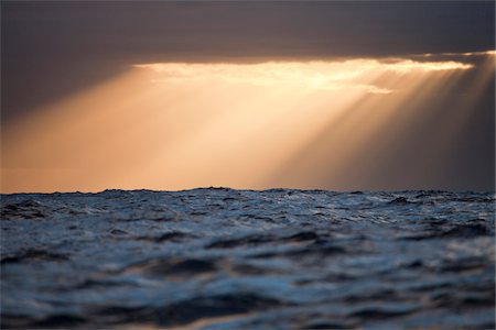 rayo de sol - Sun rays shine through clouds casting beams of light after a storm in the Atlantic Ocean Foto de stock - Sin royalties Premium, Código: 600-06782128