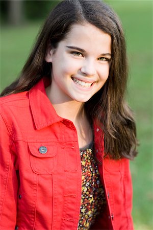 Portrait of pre-teen girl with long, brown hair, wearing red jacket, outdoors Stock Photo - Premium Royalty-Free, Code: 600-06847437