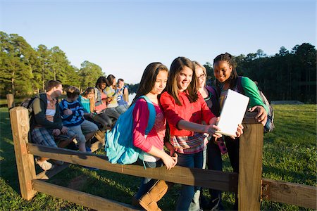 preteen friends not adults - Group of pre-teens sitting on fence, looking at tablet computer and cellphones, outdoors Stock Photo - Premium Royalty-Free, Code: 600-06847446