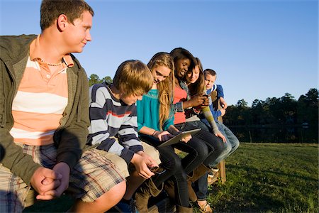 simsearch:614-06002419,k - Group of pre-teens sitting on fence, looking at tablet computer and cellphones, outdoors, Florida, USA Stock Photo - Premium Royalty-Free, Code: 600-06841924