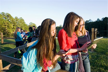 simsearch:600-06752514,k - Group of pre-teens sitting on fence, looking at tablet computers and cellphones, outdoors, Florida, USA Photographie de stock - Premium Libres de Droits, Code: 600-06841922