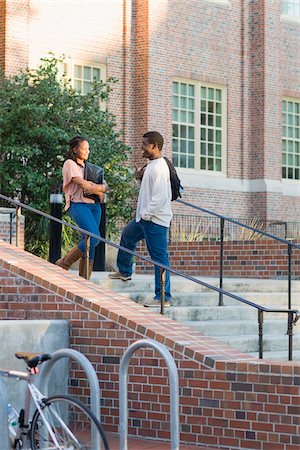 Young man and young woman outdoors on college campus, talking on stairs, Florida, USA Stock Photo - Premium Royalty-Free, Code: 600-06841933