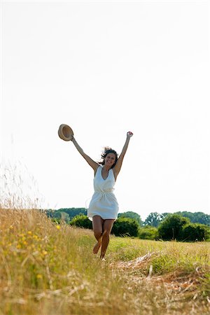 Teenaged girl holding straw hat with arms in air, walking in field on a summer day, Germany Stock Photo - Premium Royalty-Free, Code: 600-06899846