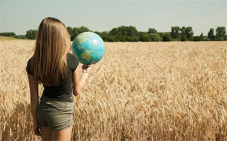 Backview of teenaged girl standing in wheat field, holding globe, Germany Stock Photo - Premium Royalty-Free, Code: 600-06899858