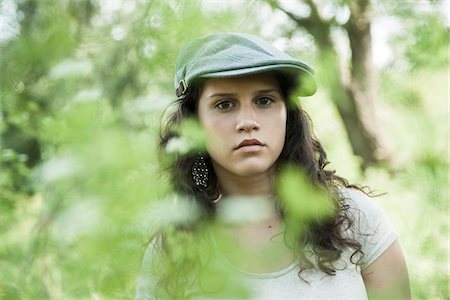 simsearch:700-07567431,k - Close-up portrait of teenaged girl wearing cap outdoors, looking at camera through leaves, Germany Stock Photo - Premium Royalty-Free, Code: 600-06899852