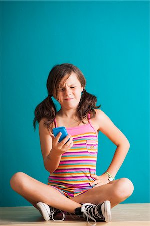 Girl sitting on floor looking at smartphone, Germany Stock Photo - Premium Royalty-Free, Code: 600-06899905