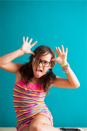 sacando la lengua - Portrait of girl sitting on floor making funny faces, Germany Foto de stock - Sin royalties Premium, Código: 600-06899910