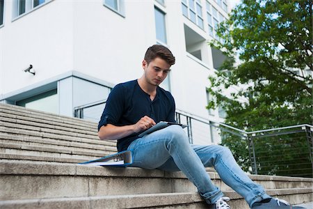 Young man sitting on steps outdoors, using tablet computer, Germany Foto de stock - Sin royalties Premium, Código: 600-06899929