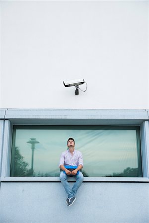 Young man sitting on ledge outdoors, Germany Photographie de stock - Premium Libres de Droits, Code: 600-06899939