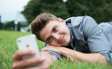 Close-up of young man lying on grass, looking at cell phone, Germany Foto de stock - Sin royalties Premium, Código: 600-06899946