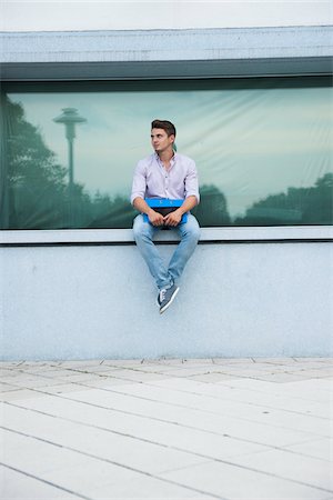 Young man sitting on ledge outdoors, Germany Foto de stock - Sin royalties Premium, Código: 600-06899940