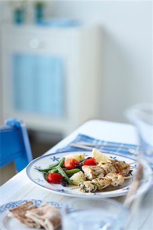 Greek Supper with Chicken Souvlaki, Green Beans, Tomatoes, Potatoes, Pita Bread, and Lemon Wedge on Table Foto de stock - Sin royalties Premium, Código: 600-06892687