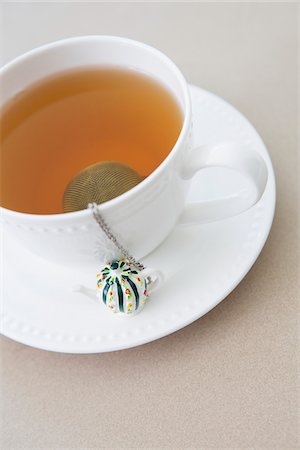 cup of tea with tea infuser and loose tea leaves on saucer Stock Photo - Premium Royalty-Free, Code: 600-06967771