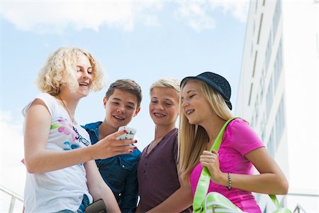 simsearch:600-07192159,k - Group of teenagers standing outdoors looking at cell phone and talking, Germany Stock Photo - Premium Royalty-Free, Code: 600-06961061