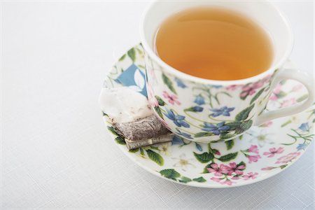 Cup of tea in pretty floral cup with saucer and used tea bag, on white background, studio shot Photographie de stock - Premium Libres de Droits, Code: 600-07067015