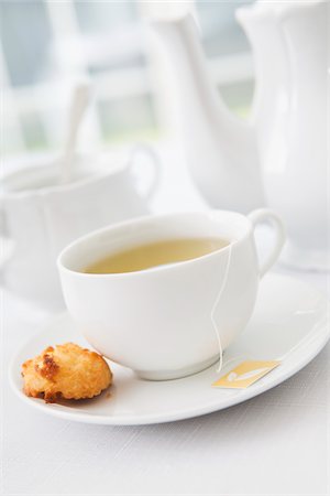 simsearch:600-07803121,k - Cup of tea in porcelain white teacup with saucer, sugar bowl, teapot and plate of coconut macaroons, studio shot Stock Photo - Premium Royalty-Free, Code: 600-07067034