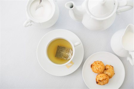 simsearch:600-07066881,k - Cup of tea in porcelain white teacup with saucer, sugar bowl, creamer, teapot and plate of coconut macaroons, studio shot Stock Photo - Premium Royalty-Free, Code: 600-07067035