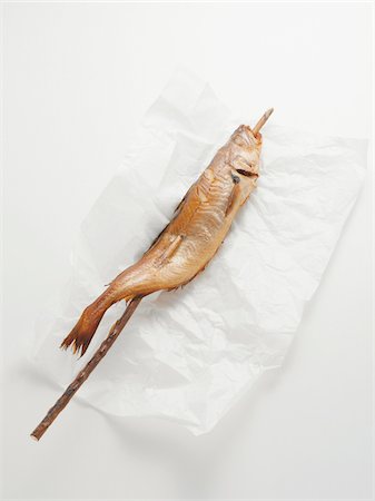 Fried mackerel pike fish on stick, on paper wrapper, studio shot Photographie de stock - Premium Libres de Droits, Code: 600-07067123