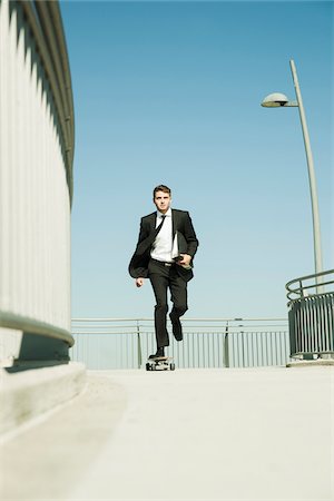 skateboard - Businessman skateboarding on walkway holding binder, Germany Stock Photo - Premium Royalty-Free, Code: 600-07117114