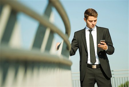 shirt - Portrait of businessman standing by railing and looking at smartphone, Germany Foto de stock - Sin royalties Premium, Código: 600-07117111