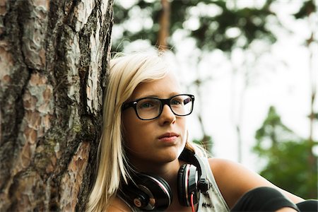 portrait kid - Close-up portrait of girl wearing eyeglasses, sitting next to tree in park, with headphones around neck, Germany Stock Photo - Premium Royalty-Free, Code: 600-07117129