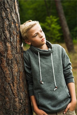 Portrait of boy standing in front of tree in park, looking into the distance, Germany Stock Photo - Premium Royalty-Free, Code: 600-07117123