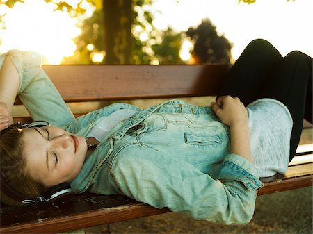 simsearch:600-07110648,k - Young Woman Lying on Park Bench Listening to Music with Headphones, Mannehim, Baden-Wurttemberg, Germany Foto de stock - Sin royalties Premium, Código: 600-07110650