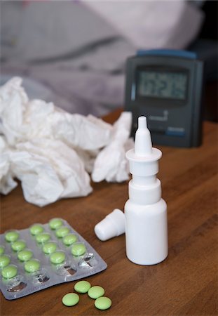 Medication and crumpled facial tissues and alarm clock on bedside table, studio shot Foto de stock - Sin royalties Premium, Código: 600-07148133