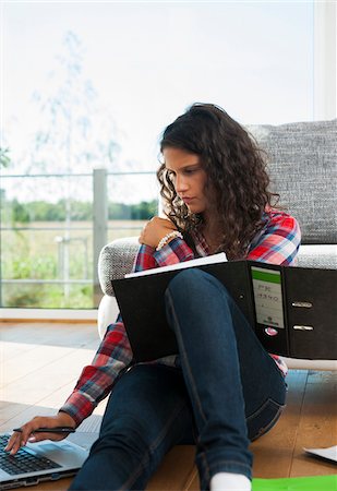 Teenage girl sitting on floor next to sofa, using laptop computer, Germany Stock Photo - Premium Royalty-Free, Code: 600-07148163
