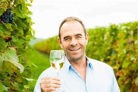 Portrait of vintner holding glass of wine in vineyard, smiling and looking at camera, Rhineland-Palatinate, Germany Foto de stock - Sin royalties Premium, Código: 600-07148212