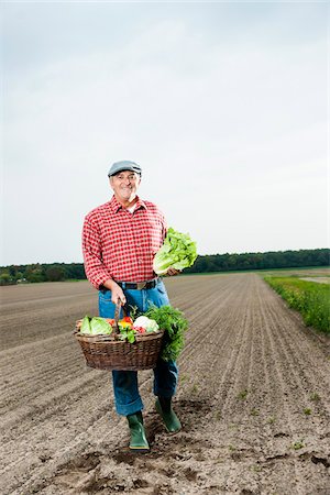 Farmer standing in field with basket of fresh vegetables, smiling and looking at camera, Hesse, Germany Stock Photo - Premium Royalty-Free, Code: 600-07148225