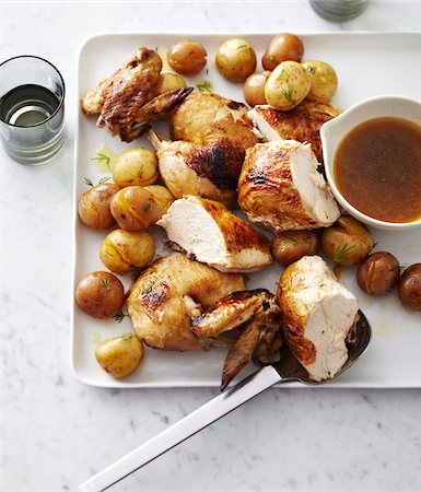 simsearch:600-07156153,k - Faux-Tisserie Chicken cut into pieces with roasted potatoes on platter with gravy, studio shot Stock Photo - Premium Royalty-Free, Code: 600-07156153