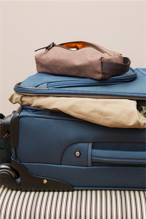 packing for travel - Men's brown toiletry travel bag on top of packed suitcase on bed, USA Stock Photo - Premium Royalty-Free, Code: 600-07199739