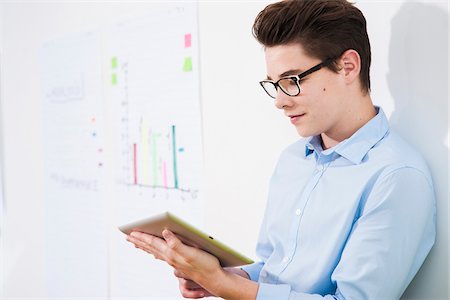 Business apprentice looking at tablet computer in office, Germany Stock Photo - Premium Royalty-Free, Code: 600-07199808