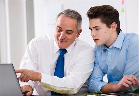 Businessman showing computer data to apprentice in office, Germany Stock Photo - Premium Royalty-Free, Code: 600-07199802