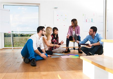 simsearch:600-07200043,k - Mature businesswoman meeting with group of young business people, sitting on floor in discussion, Germany Stock Photo - Premium Royalty-Free, Code: 600-07200043