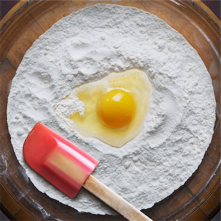 Close-up of flour and raw egg on glass dish with spatula, studio shot Stock Photo - Premium Royalty-Free, Code: 600-07240806