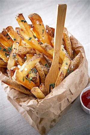 patatas fritas - Seasoned French Fries in Paper Bag with Wooden Fork and Ketchup, Studio Shot Foto de stock - Sin royalties Premium, Código: 600-07278861