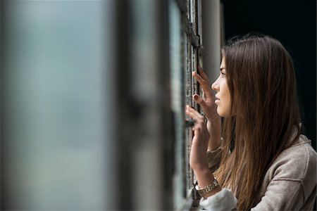simsearch:700-07364036,k - Portrait of young woman standing and looking out of window day dreaming, Germany Stock Photo - Premium Royalty-Free, Code: 600-07278938