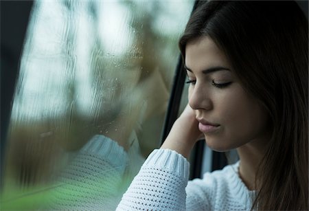 simsearch:600-07278937,k - Portrait of young woman sitting inside car next to window, looking downwards and day dreaming on overcast day, Germany Stock Photo - Premium Royalty-Free, Code: 600-07278931