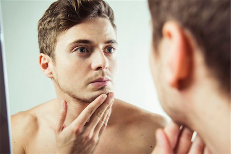 simsearch:600-07278944,k - Close-up of young man looking at reflection in bathroom mirror, studio shot Foto de stock - Sin royalties Premium, Código: 600-07278940