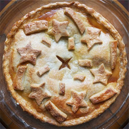 simsearch:400-07625362,k - Overhead view of freshly baked apple pie with star shaped cut-outs on top, studio shot Stock Photo - Premium Royalty-Free, Code: 600-07310951