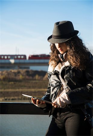 picture of a person wearing a black hat - Teenage girl standing outdoors, wearing fedora and using tablet computer, Germany Stock Photo - Premium Royalty-Free, Code: 600-07310985