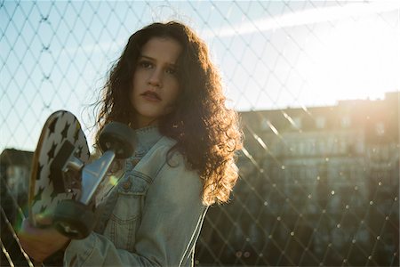 simsearch:600-07310985,k - Portrait of teenage girl standing outdoors next to chain link fence, holding skateboard, Germany Stock Photo - Premium Royalty-Free, Code: 600-07311004