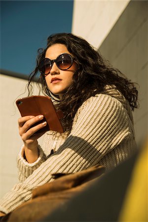 simsearch:600-07311133,k - Close-up portrait of teenage girl outdoors wearing sunglasses, sitting next to building and holding smart phone, Germany Stock Photo - Premium Royalty-Free, Code: 600-07311098