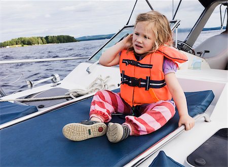 3 year old girl in orange life jacket sitting on top of motorboat, Sweden Stock Photo - Premium Royalty-Free, Code: 600-07311130