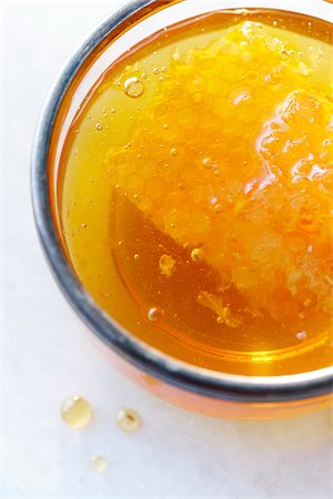 Close-up, overhead view of clear golden honey in a glass with a honey comb and air bubbles Fotografie stock - Premium Royalty-Free, Codice: 600-07311146