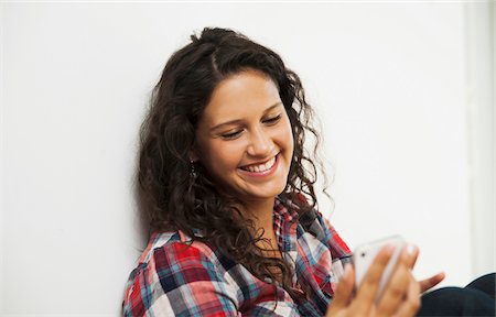 plaid - Close-up portrait of teenage girl looking at cell phone and smiling, Germany Photographie de stock - Premium Libres de Droits, Code: 600-07311421