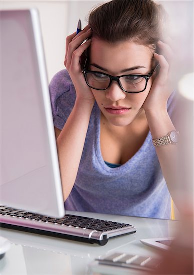 Close-up of young woman using laptop computer, looking confused, studio shot Stock Photo - Premium Royalty-Free, Artist: Uwe Umstätter, Image code: 600-07311601