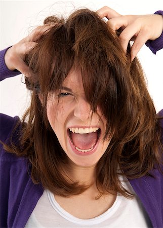 simsearch:600-07351333,k - Close-up portrait of young, brown-haired woman screaming and looking at camera with hands in her hair, studio shot on white background Stock Photo - Premium Royalty-Free, Code: 600-07348158